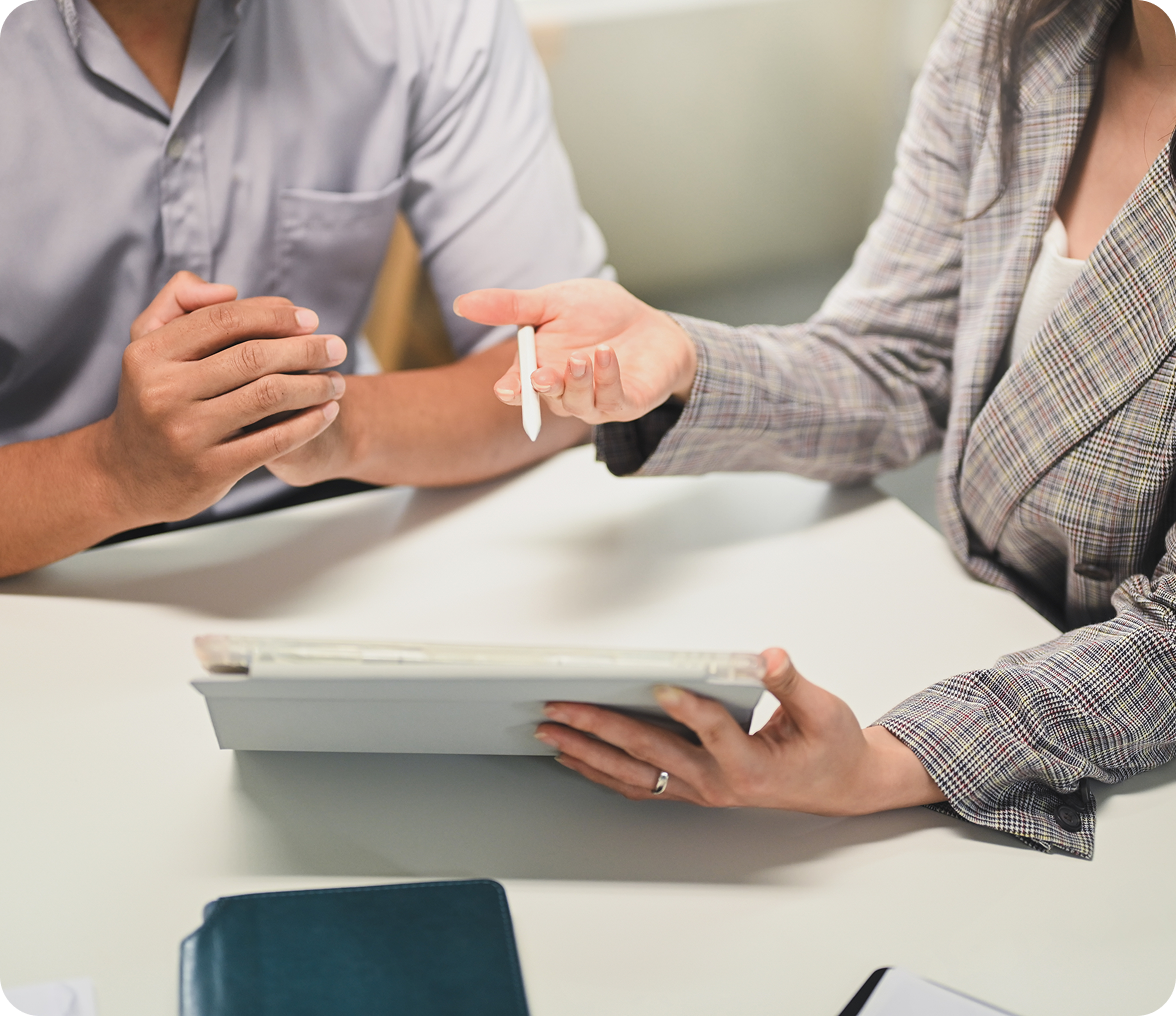 Man and woman sitting at a table, with the woman holding a tablet in her hand