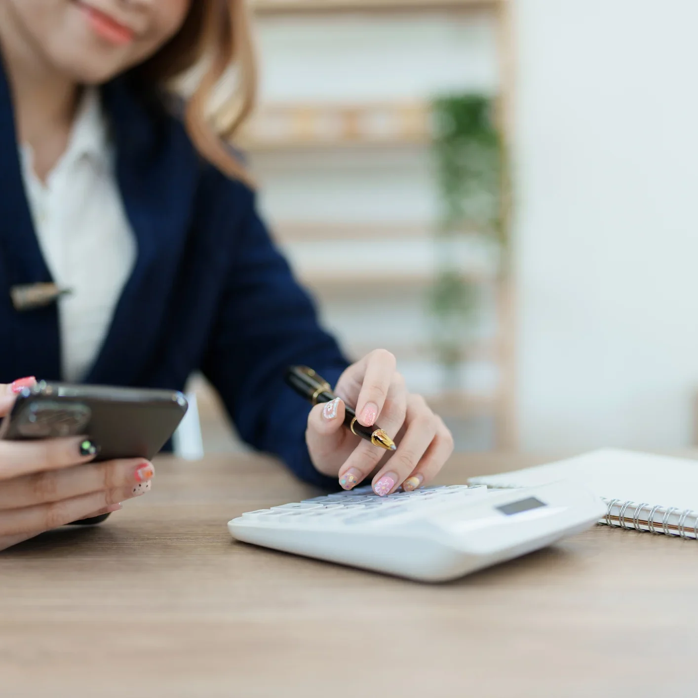 Woman sitting at a desk with a calculator and a cell phone in her hands